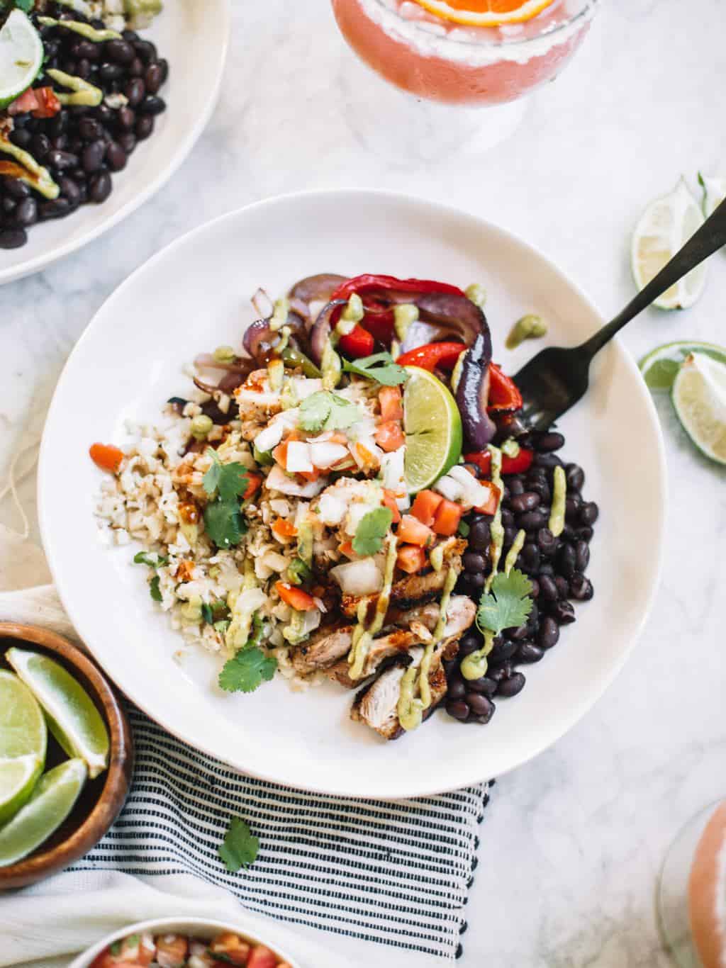 Chipotle style burrito bowls at home or for meal prep! These healthy bowls are made with cauliflower rice, juicy chicken, salsa and avocado crema!