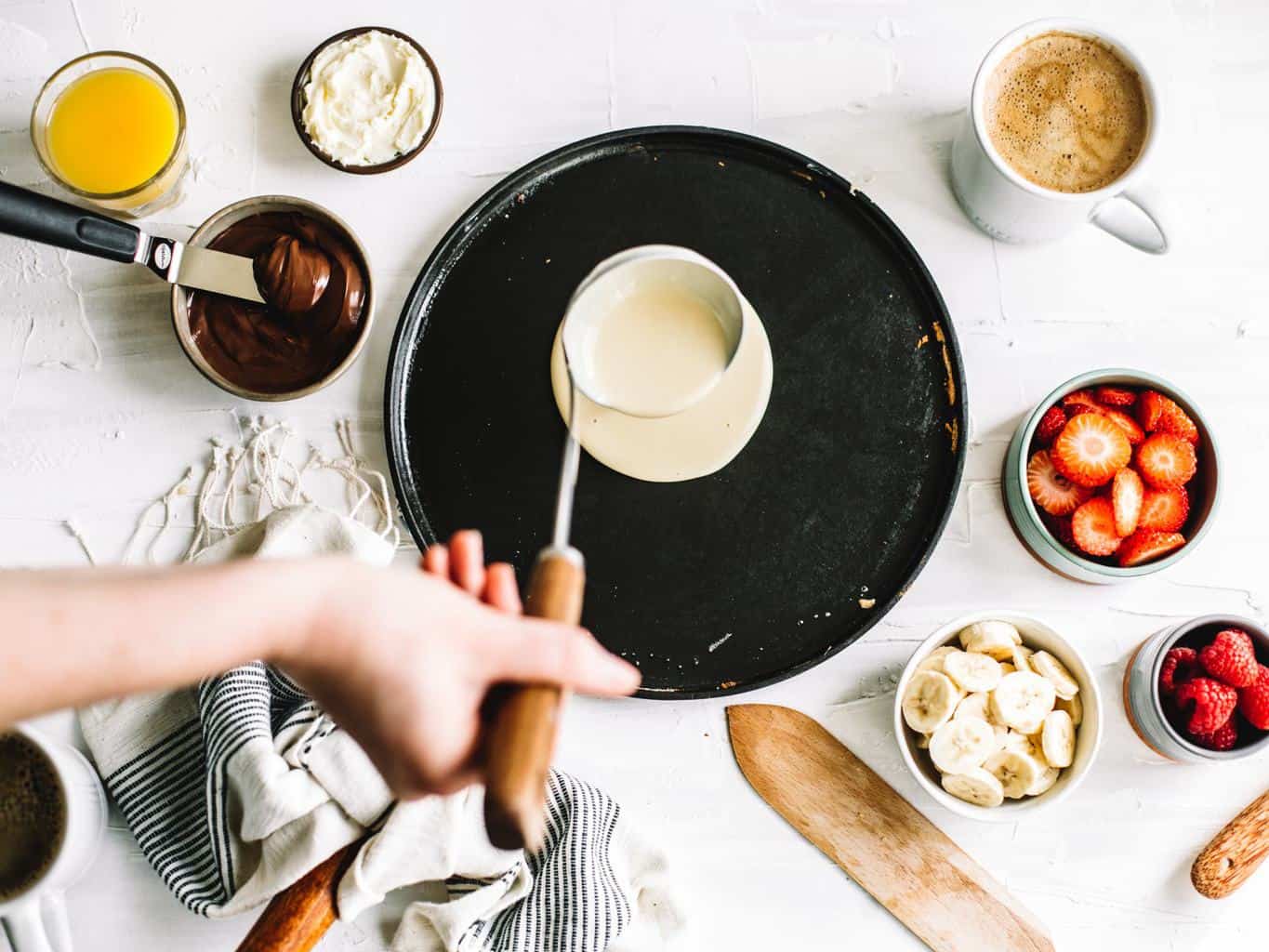 Crepes being poured on to a skillet. 