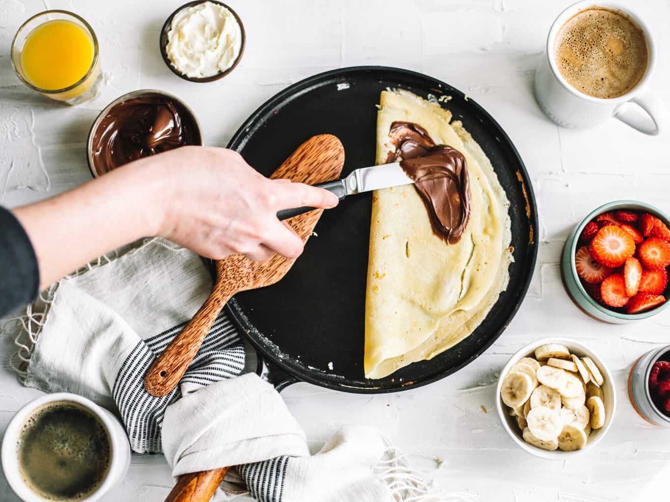 Flipped crepe with Nutella being spread. 