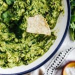 a large bowl of guacamole with a tortilla chip in it