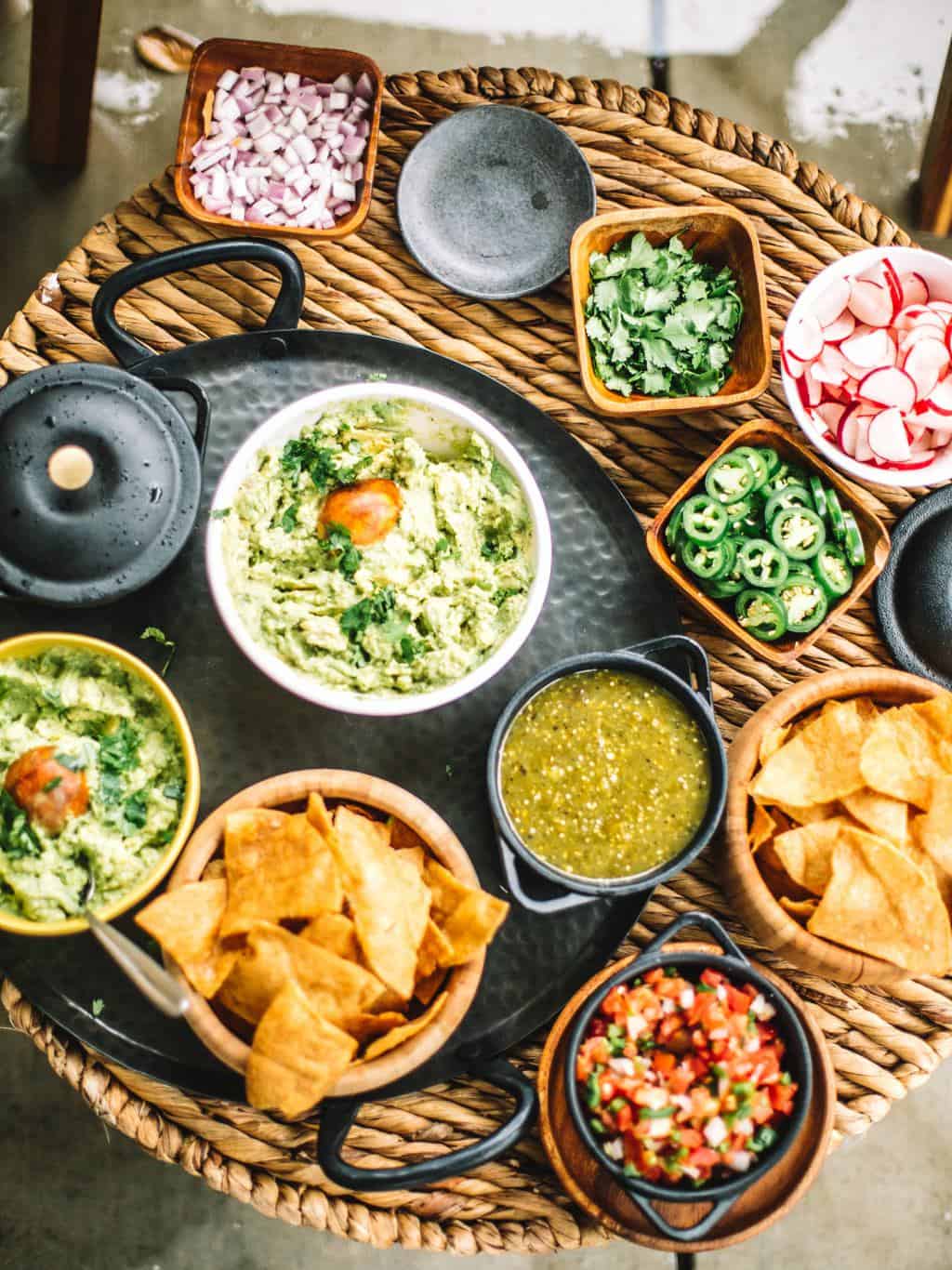 A guacamole topping station with guacamole, chips, salsas, and toppings. 