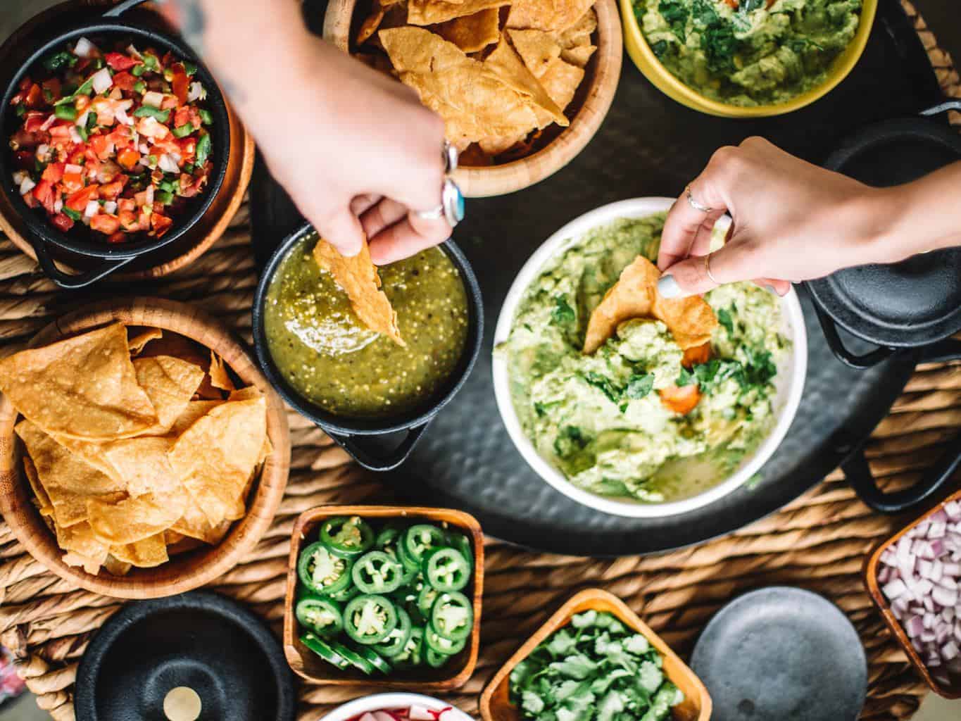 A guacamole topping station with guacamole, chips, salsas, and toppings. 