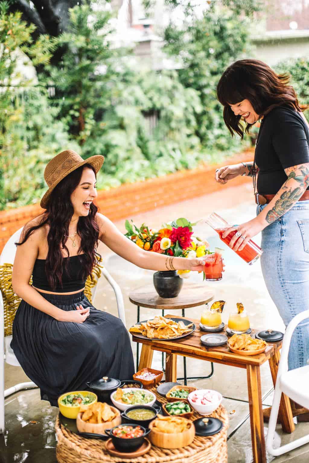 Two friends sharing margaritas at a mexican dinner party. 