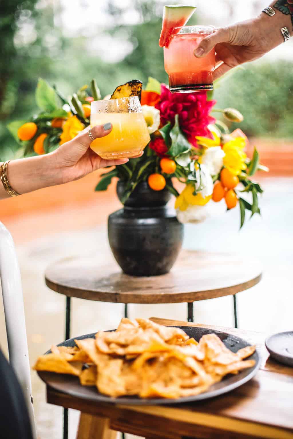 Two glasses filled with margaritas cheersing.