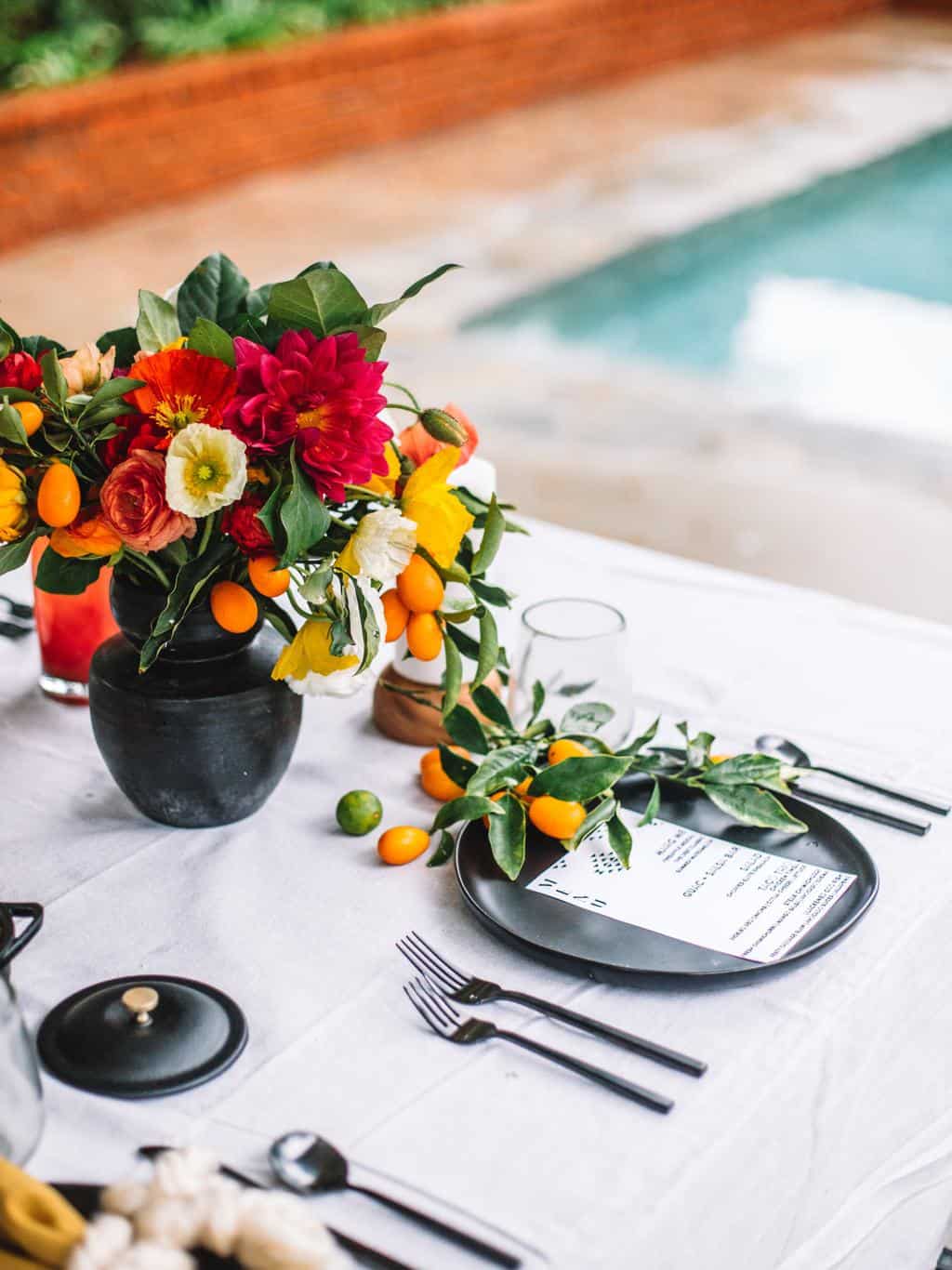 Mexican table setting with flowers, place settings and platters of tacos. 