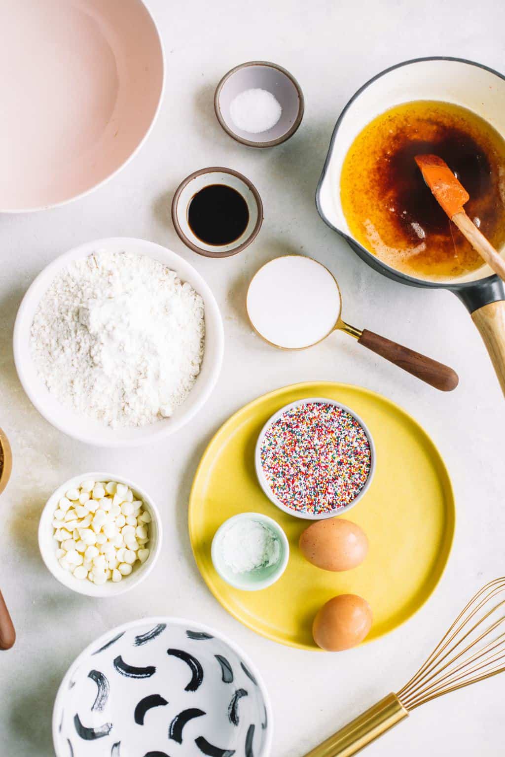 Ingredients for white chocolate sprinkle blondies in colorful bowls.