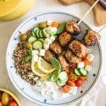 Mediterranean Greek Power Bowls in a white bowl with cherry tomatoes and yellow pot