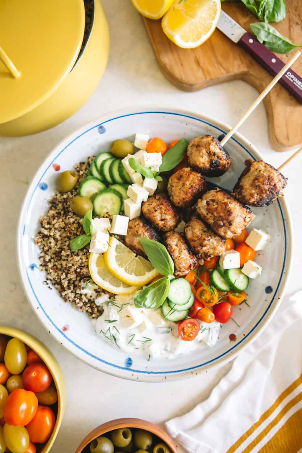 Mediterranean Greek Power Bowls in a white bowl with cherry tomatoes and yellow pot