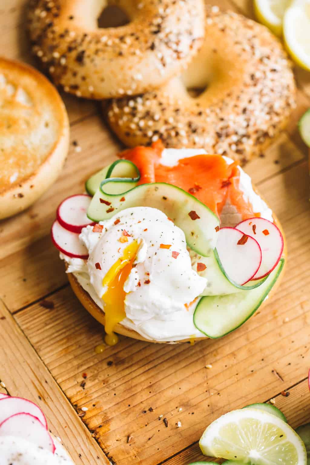 Smoked Salmon bagel with cream cheese, cucumber, radishes, and egg on a wood board