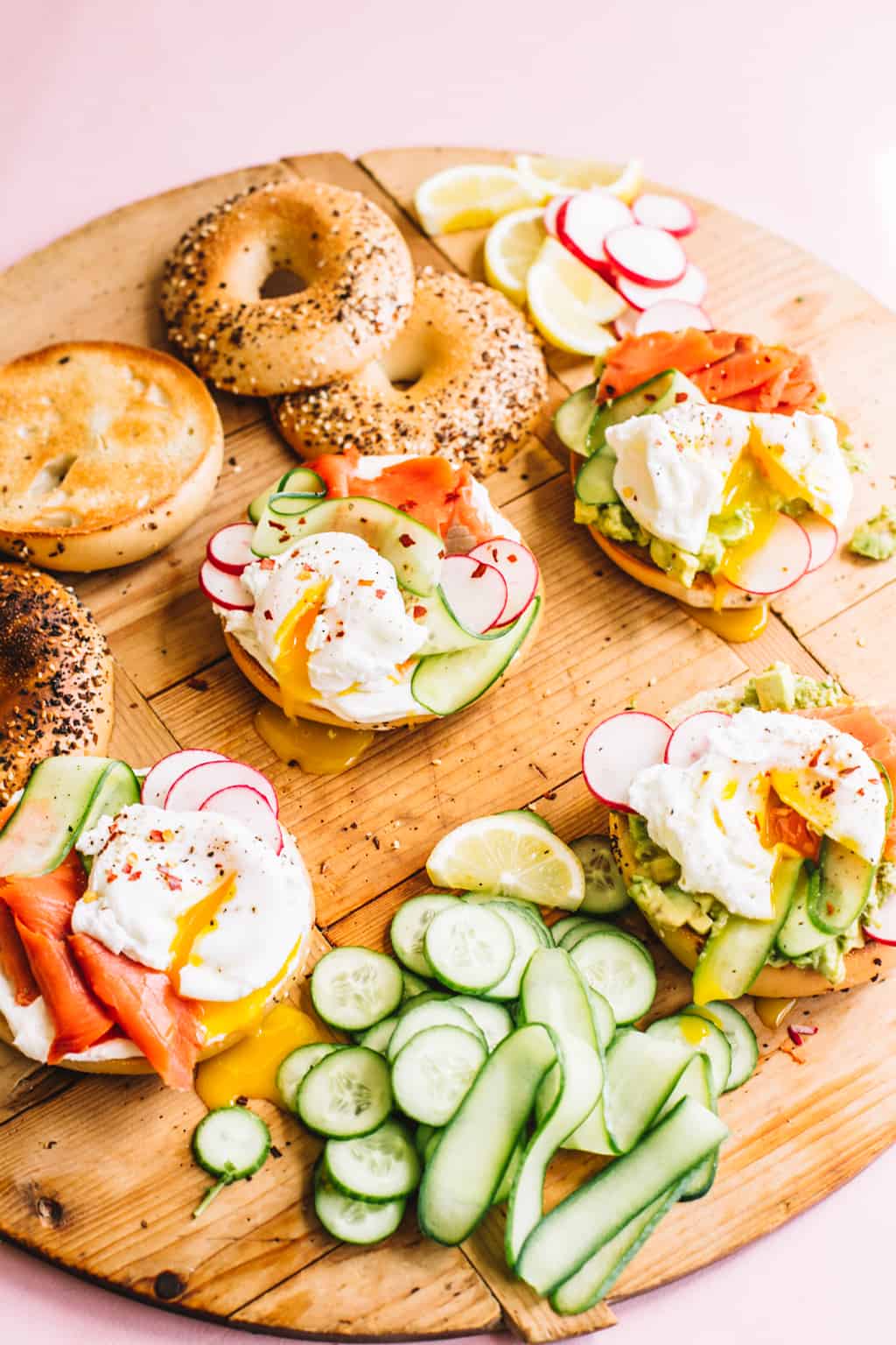 Smoked Salmon bagels with sliced cucumbers and toppings on a wood board