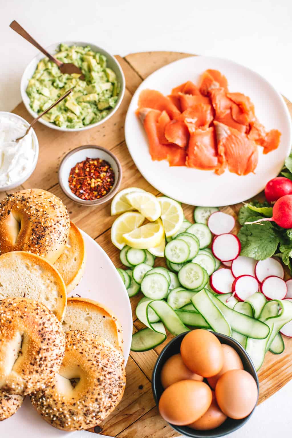 Smoked salmon in a white bowl with avocado and toppings on a wood board