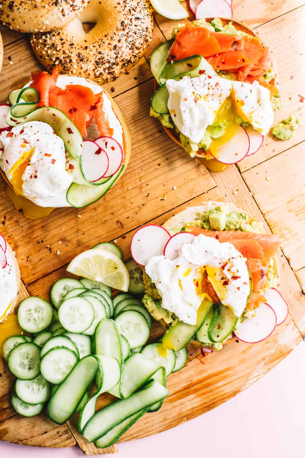 Smoked Salmon bagels with sliced cucumbers and toppings on a wood board