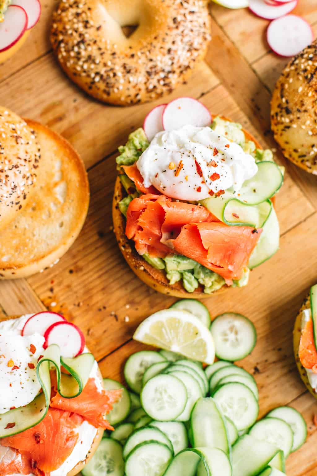 Smoked Salmon bagels with sliced cucumbers and toppings on a wood board