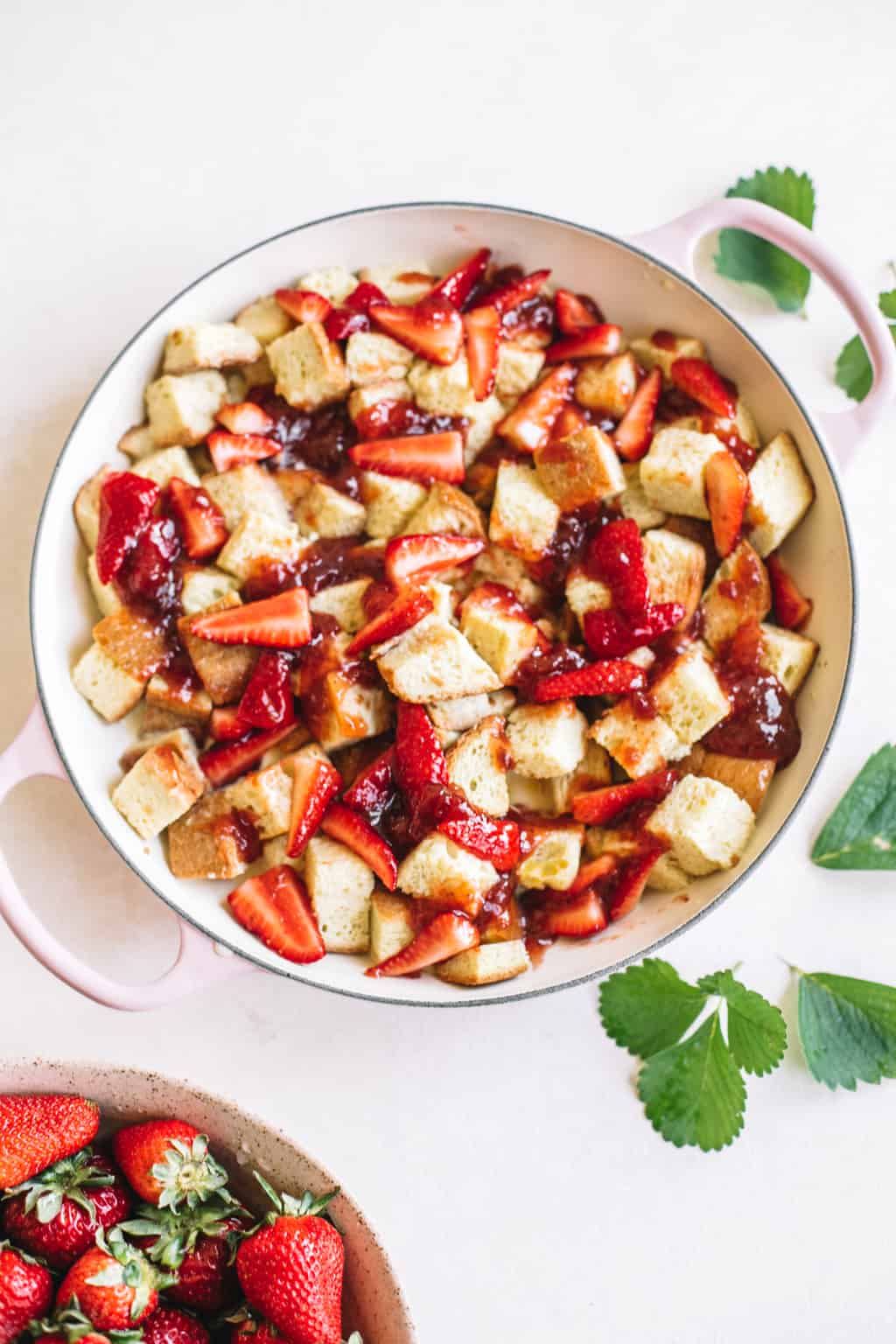 Strawberries and french toast cubes in a pink casserole dish