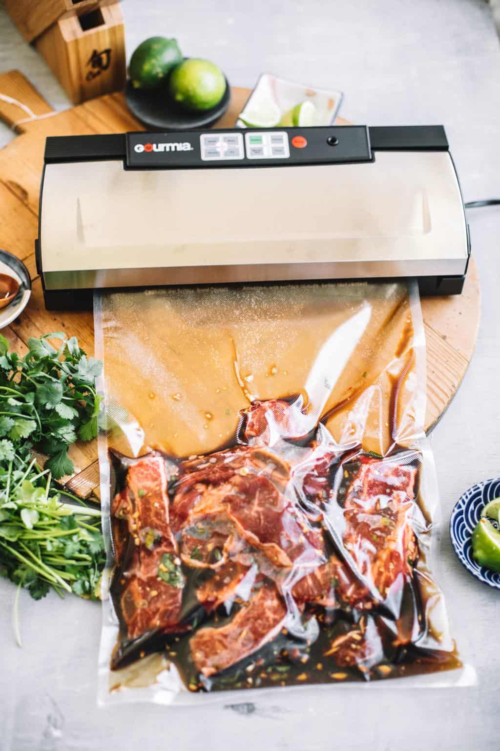 Asian short rib tacos in vaccum seal bag being sealed by a sous vide machine.