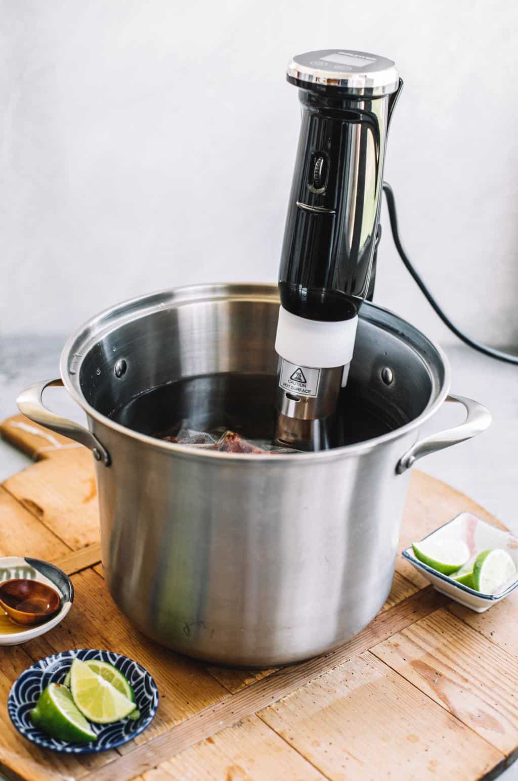 Sous vide machine inserted into large water bath in stainless steel pot