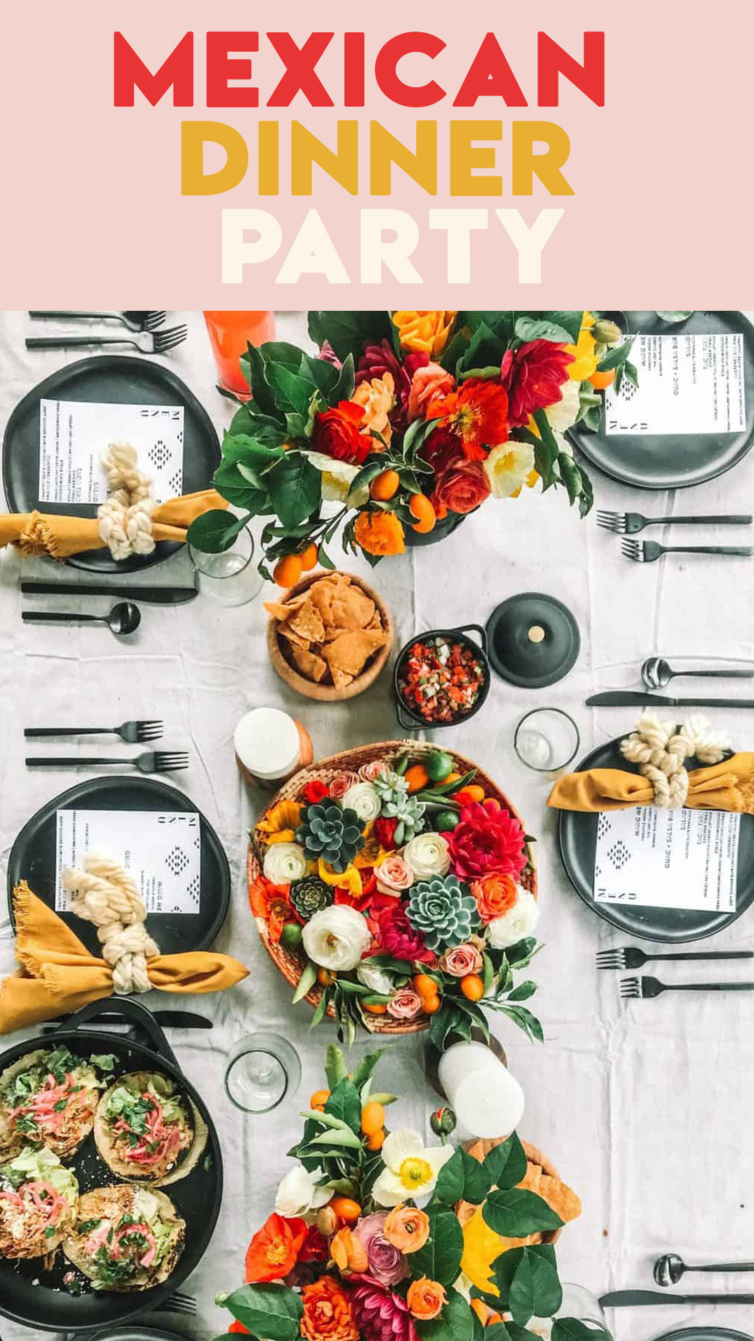 Mexican table setting with flowers, place settings and platters of tacos. 