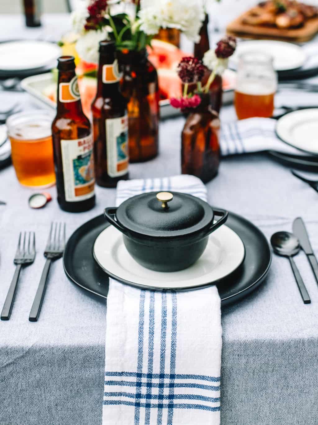 A black plate topped with a blue and white napkin on top of a tablescape. 