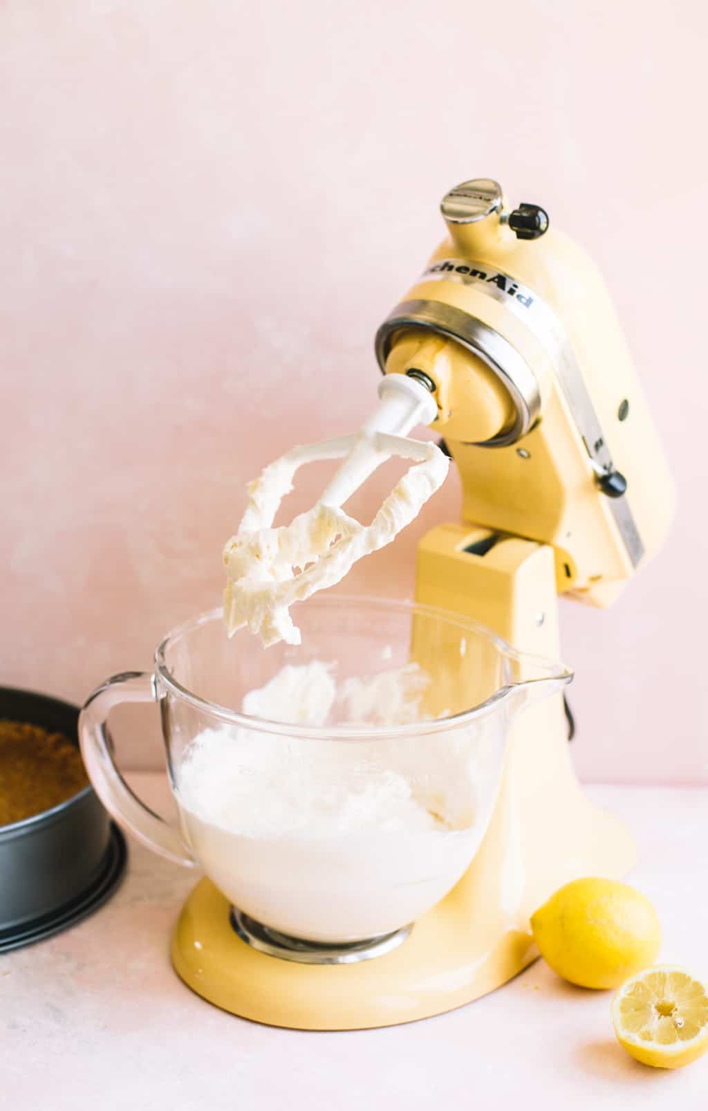 Whipped cream cheese in a yellow electric stand mixer with paddle attachment