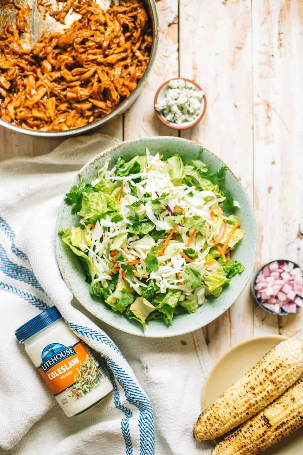 A bowl of shredded bbq chicken and a blue bowl of coleslaw salad mix.