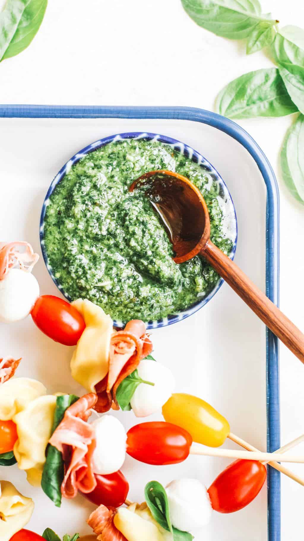 Pesto in a blue bowl with a wooden spoon