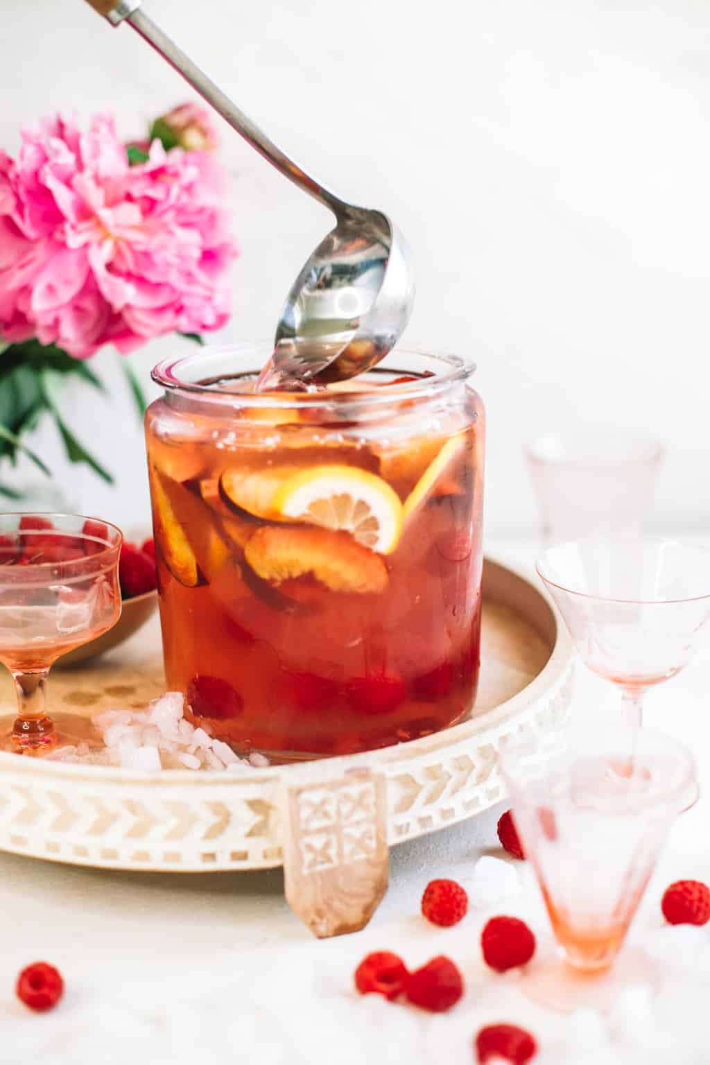 Ladle scooping out batch of sangria in a glass pitcher. 