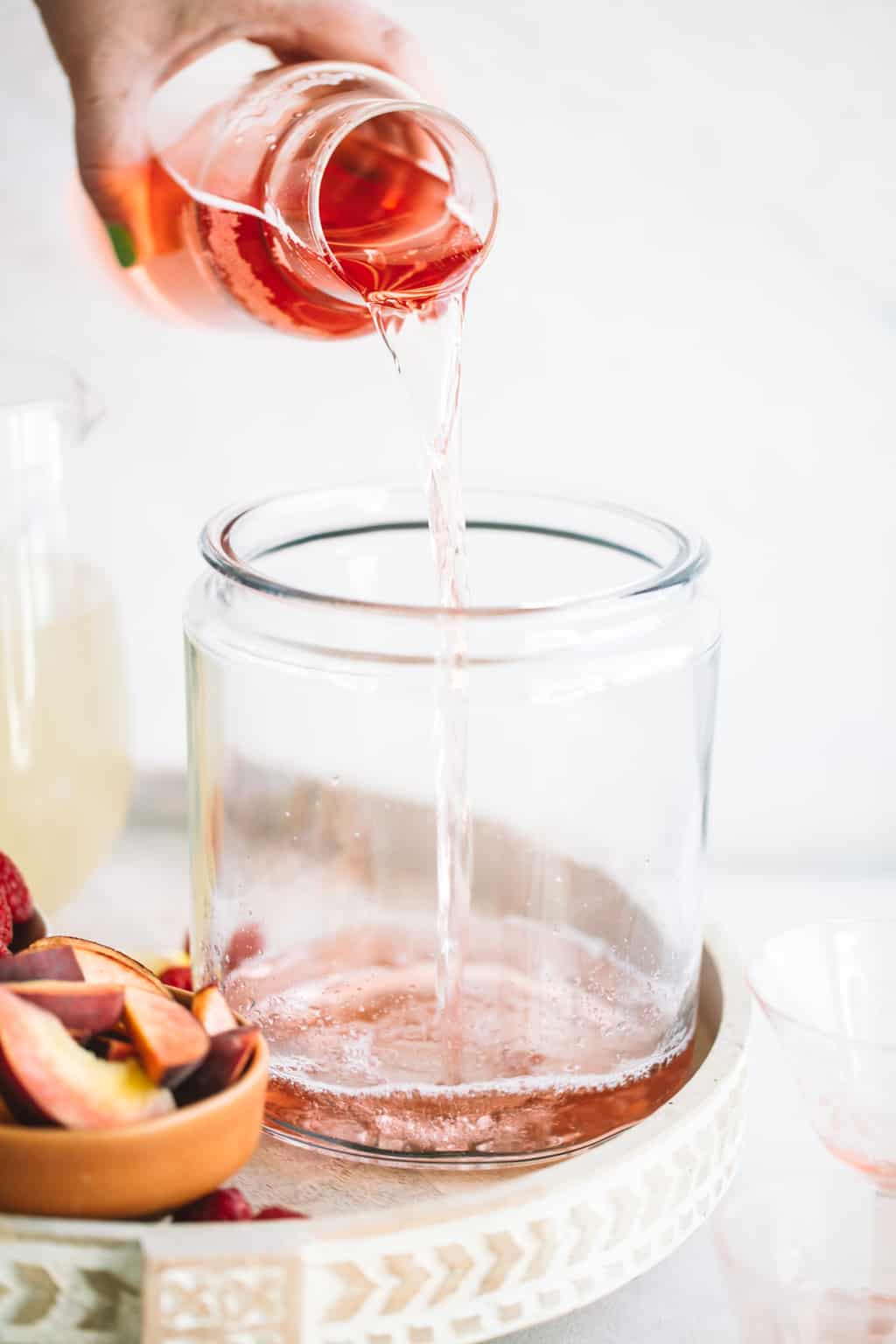 Rosè wine being poured into a glass pitcher. 