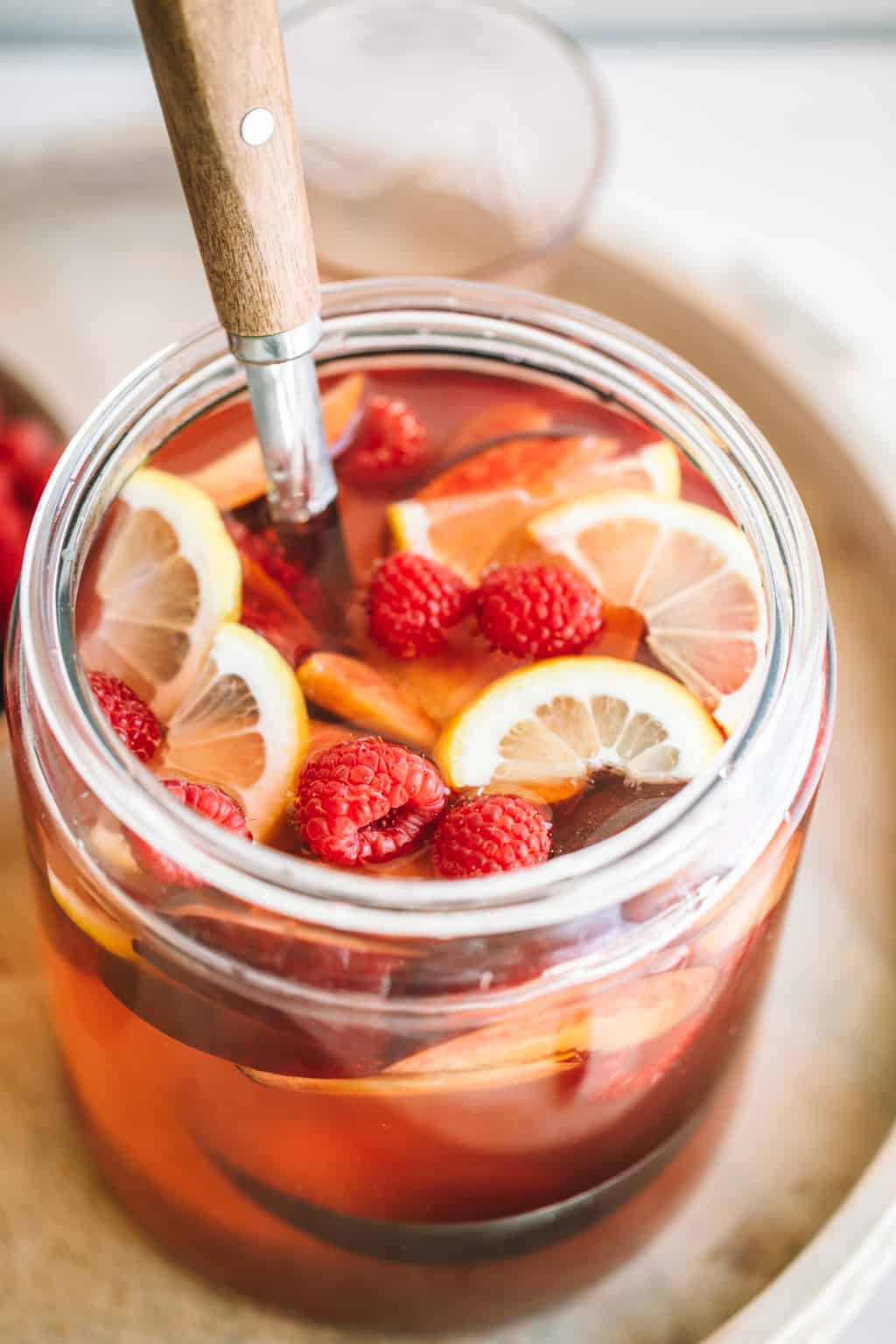 Fresh pitcher of rosè sangria with fresh raspberries and lemon slices.