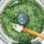 Pesto sauce in the bowl of a food processor with a spatula