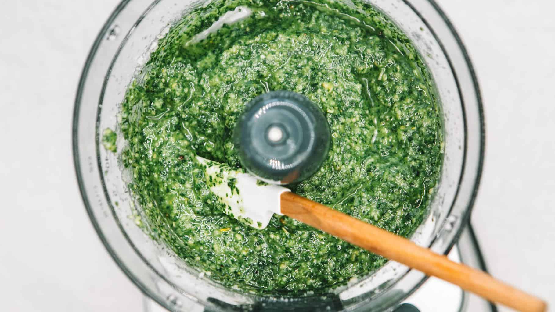 Pesto sauce in the bowl of a food processor with a spatula