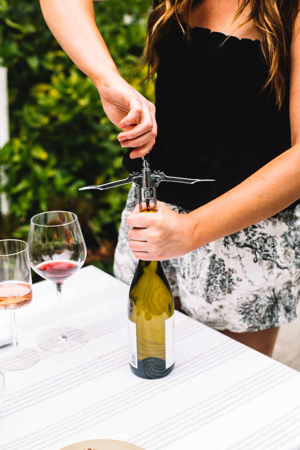 A cork screw opening up a bottle of white wine. 