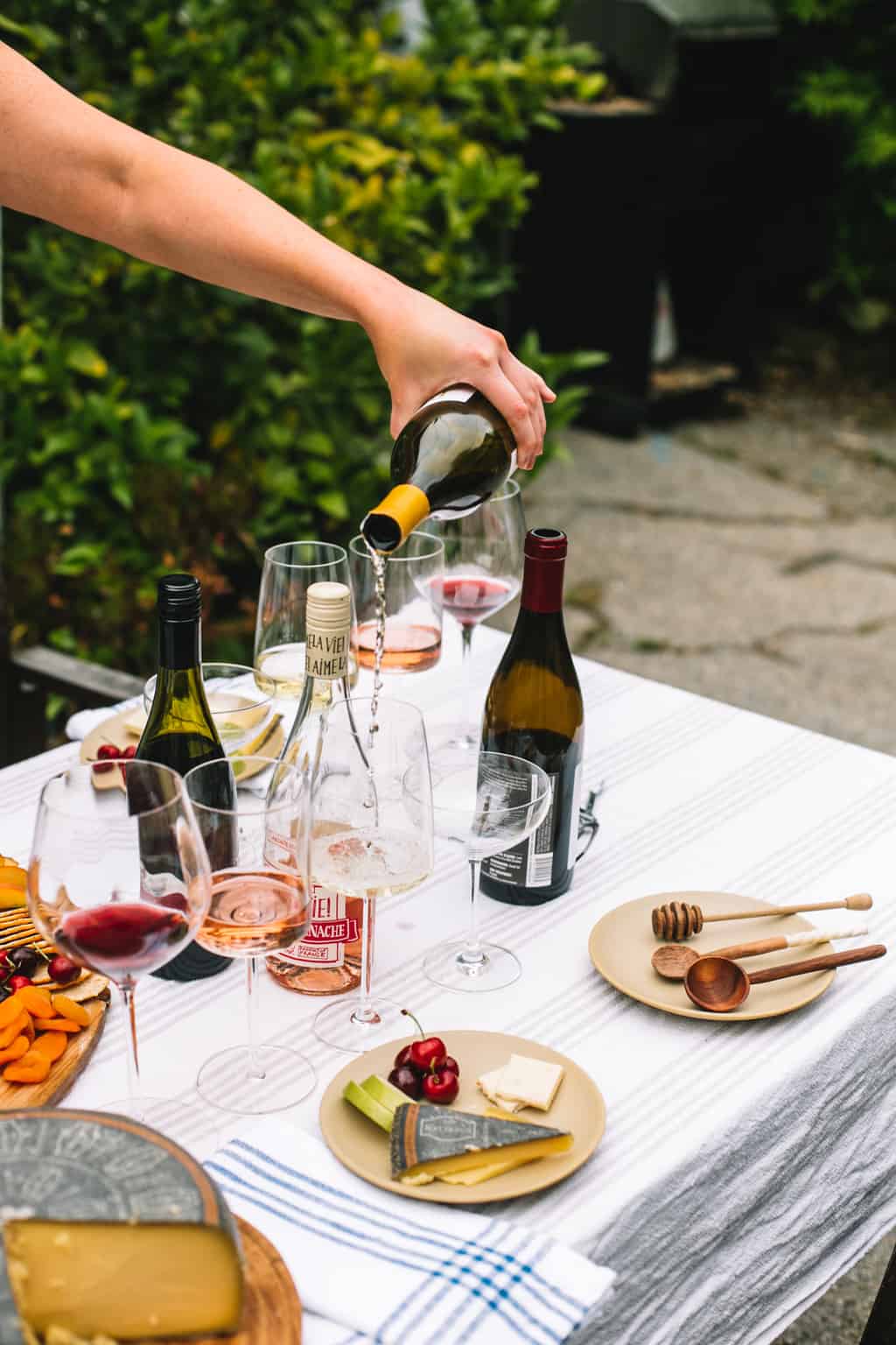 Bottle of white wine being poured into a wine glass next to other wine glasses.