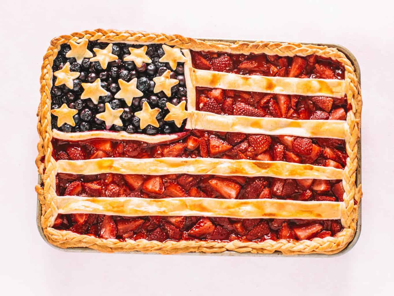 American flag pie made on a cookie sheet on a pink background.