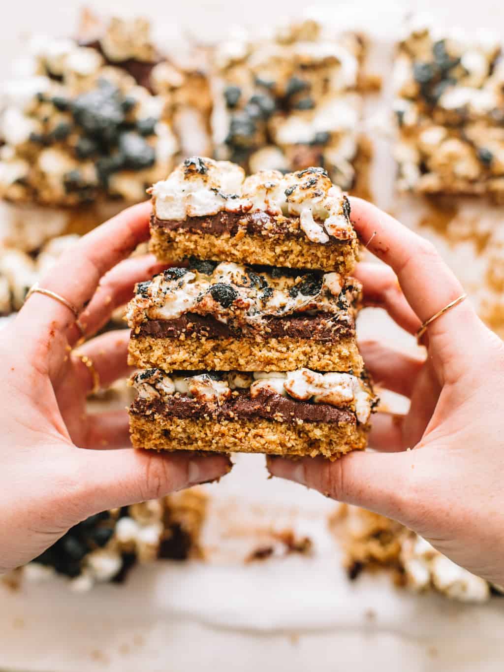 Two hands holding a stack of smores bars.