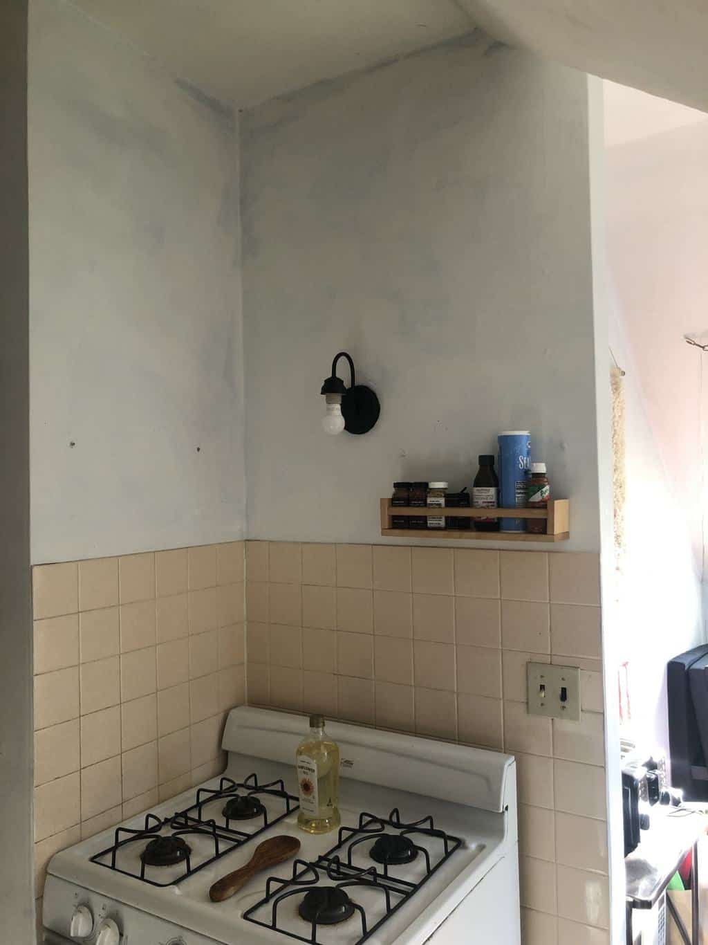 Before photo with white stove with and poorly painted walls. 