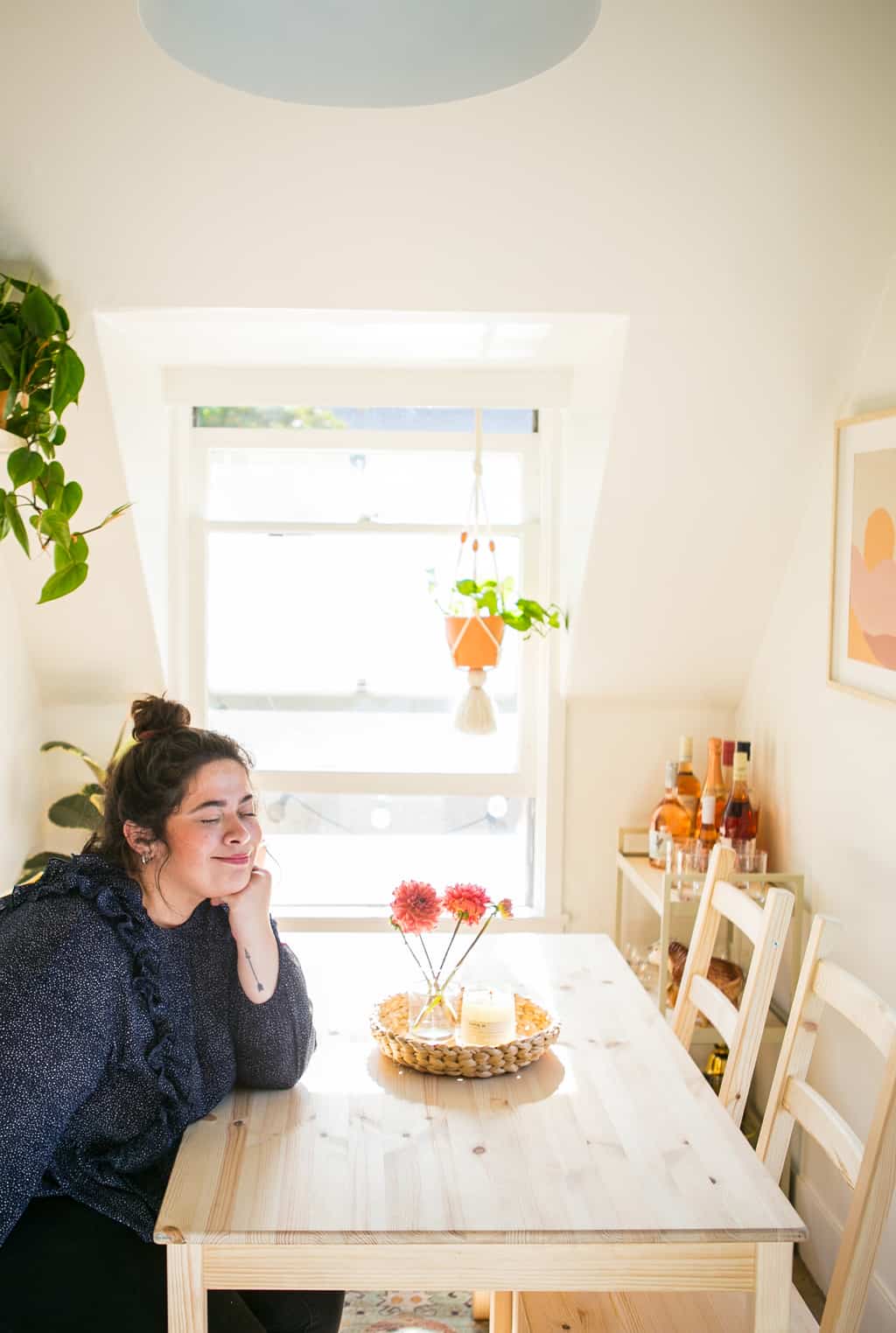 Abbie sitting in her new kitchen happy with a candle lite and a vase of flowers. 