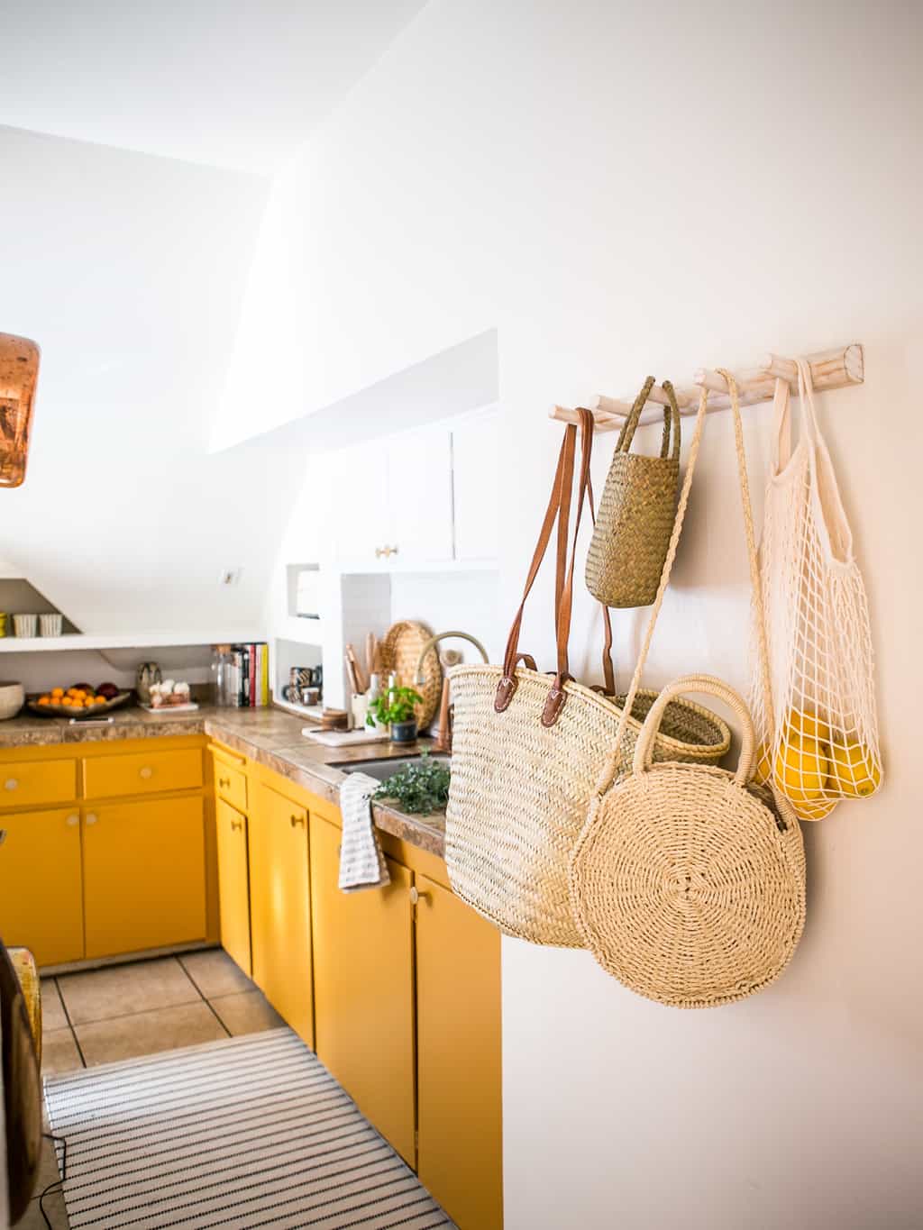 Newly finished kitchen with a rack of hanging baskets and yellow mustard cabinets. 