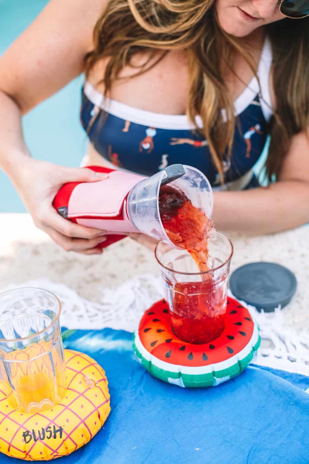 Girl in bathing suit pouring a frozen cocktail. 