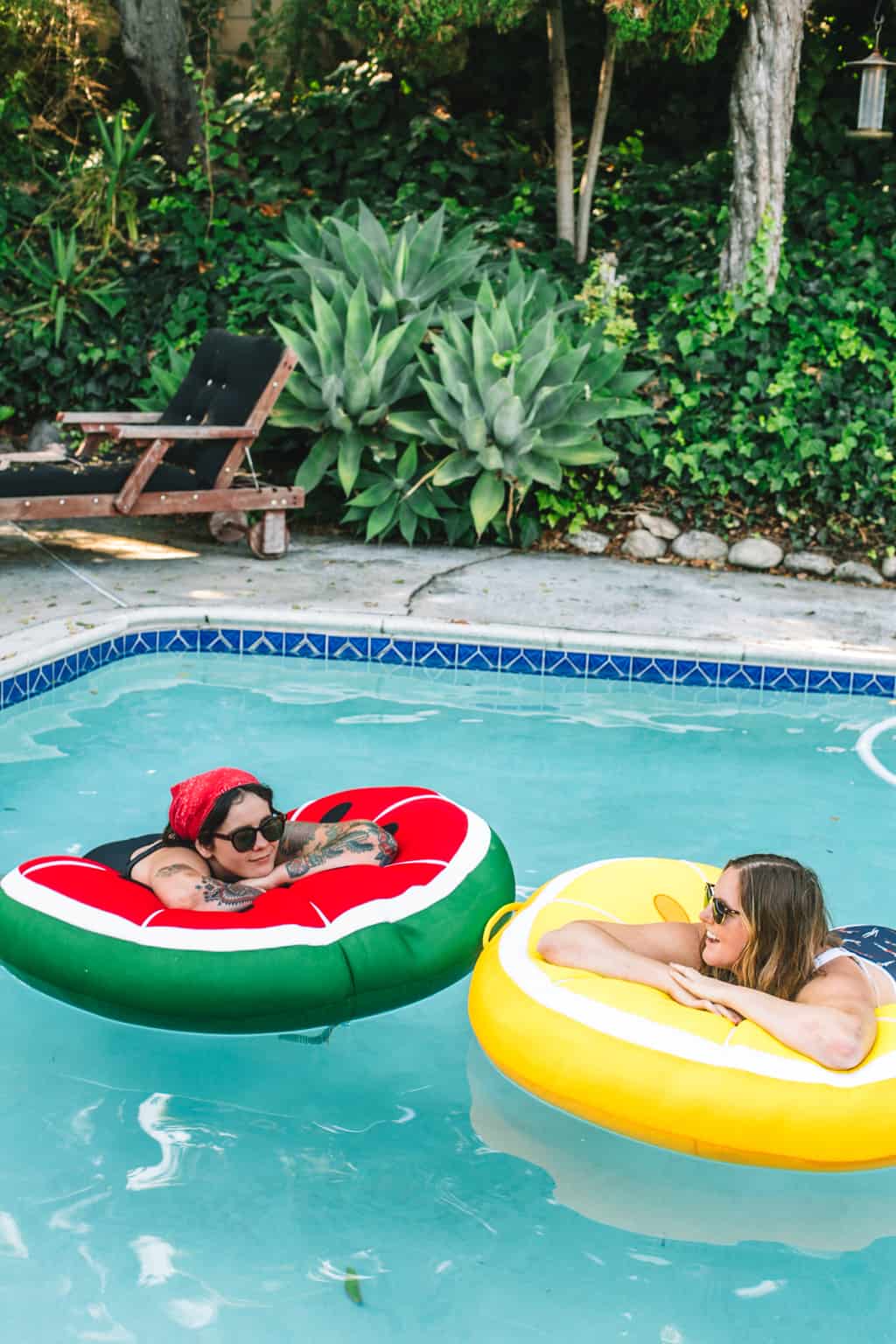 Two girls in a pool on fruit pool floats.