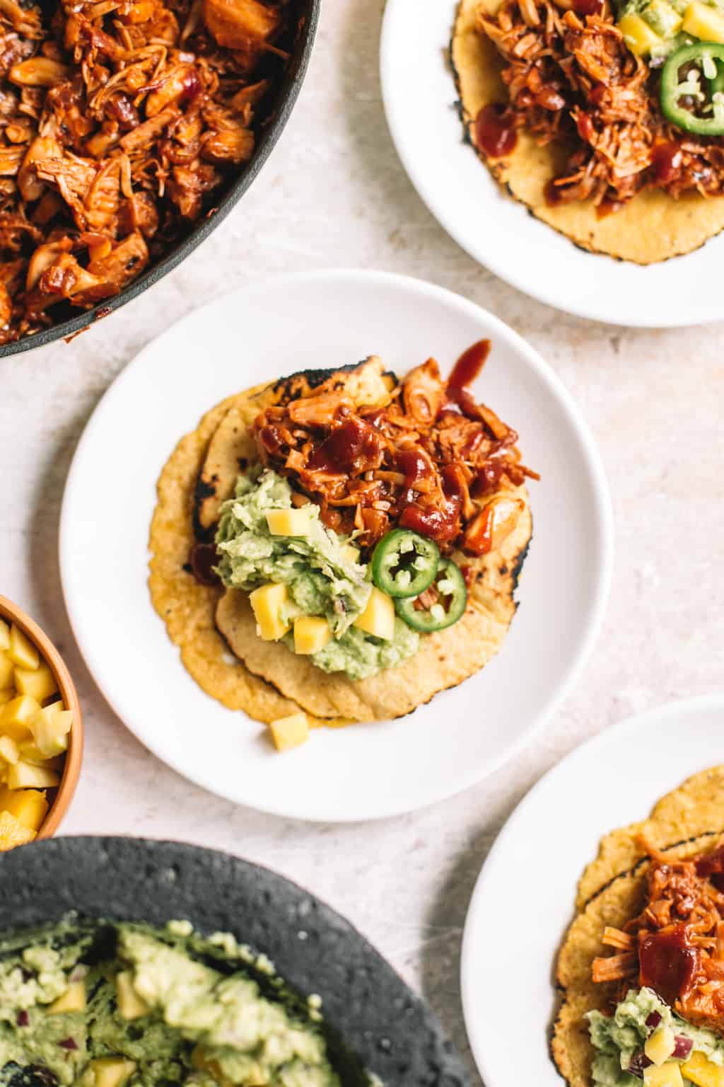 chipotle BBQ jackfruit tacos with mango guacamole in corn tortilla on white plate