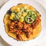 easy chipotle BBQ jackfruit tacos with mango guacamole in corn tortilla on white plate
