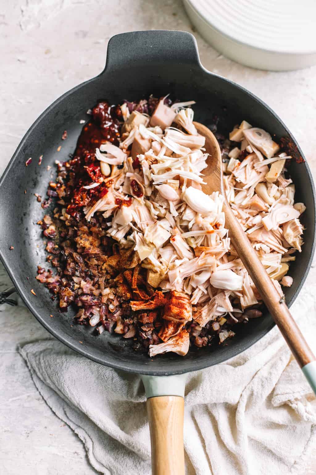 vegan jackfruit taco filling recipe in cast iron skillet with wooden spoon