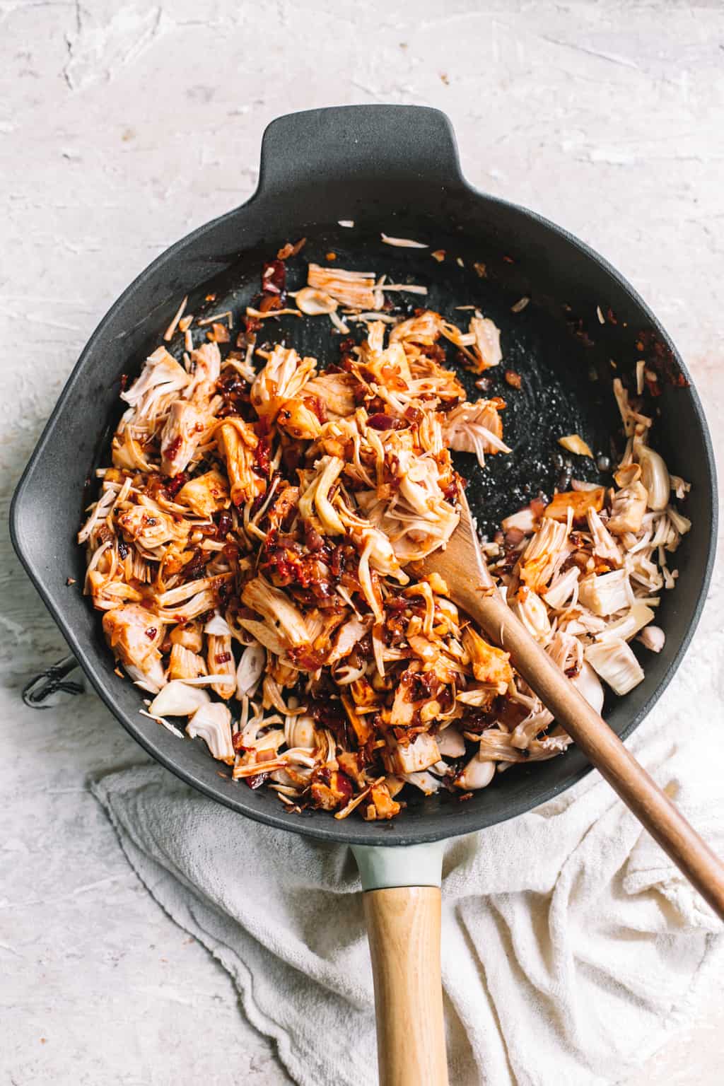 chipotle BBQ jackfruit filling in cast iron skillet with wooden spoon