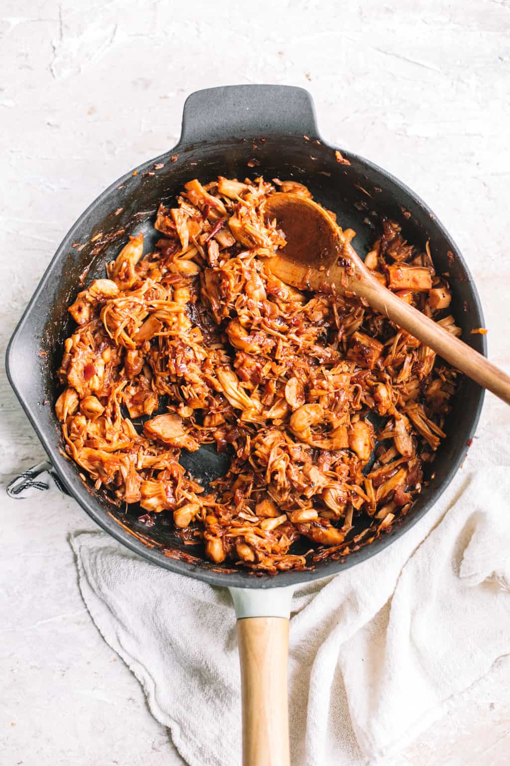 Mexican chipotle BBQ jackfruit taco filling in cast iron skillet with wooden spoon