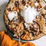 two spoons dipped in chocolate chip cookie in skillet with vanilla ice cream