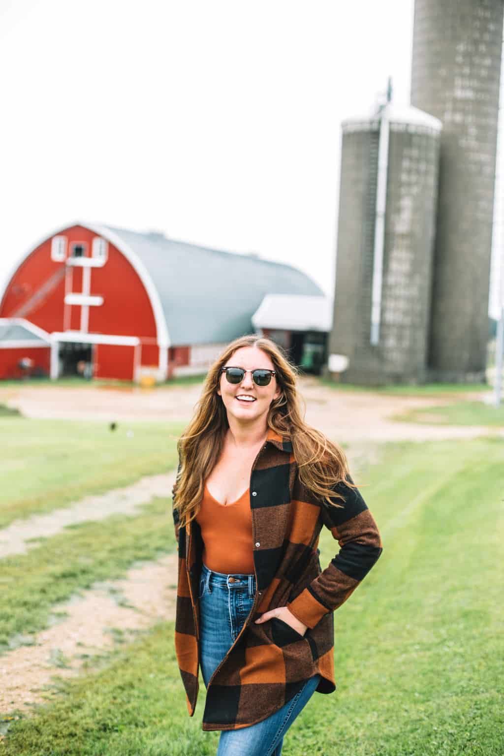 Girl standing on a farm with a barn behind her. 