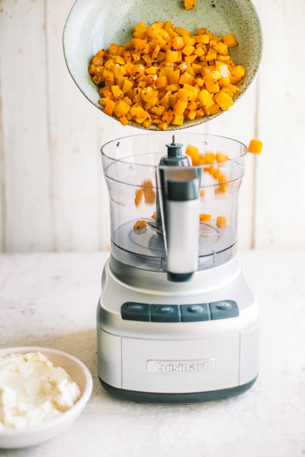 Roasted butternut squash being poured into a food processor. 