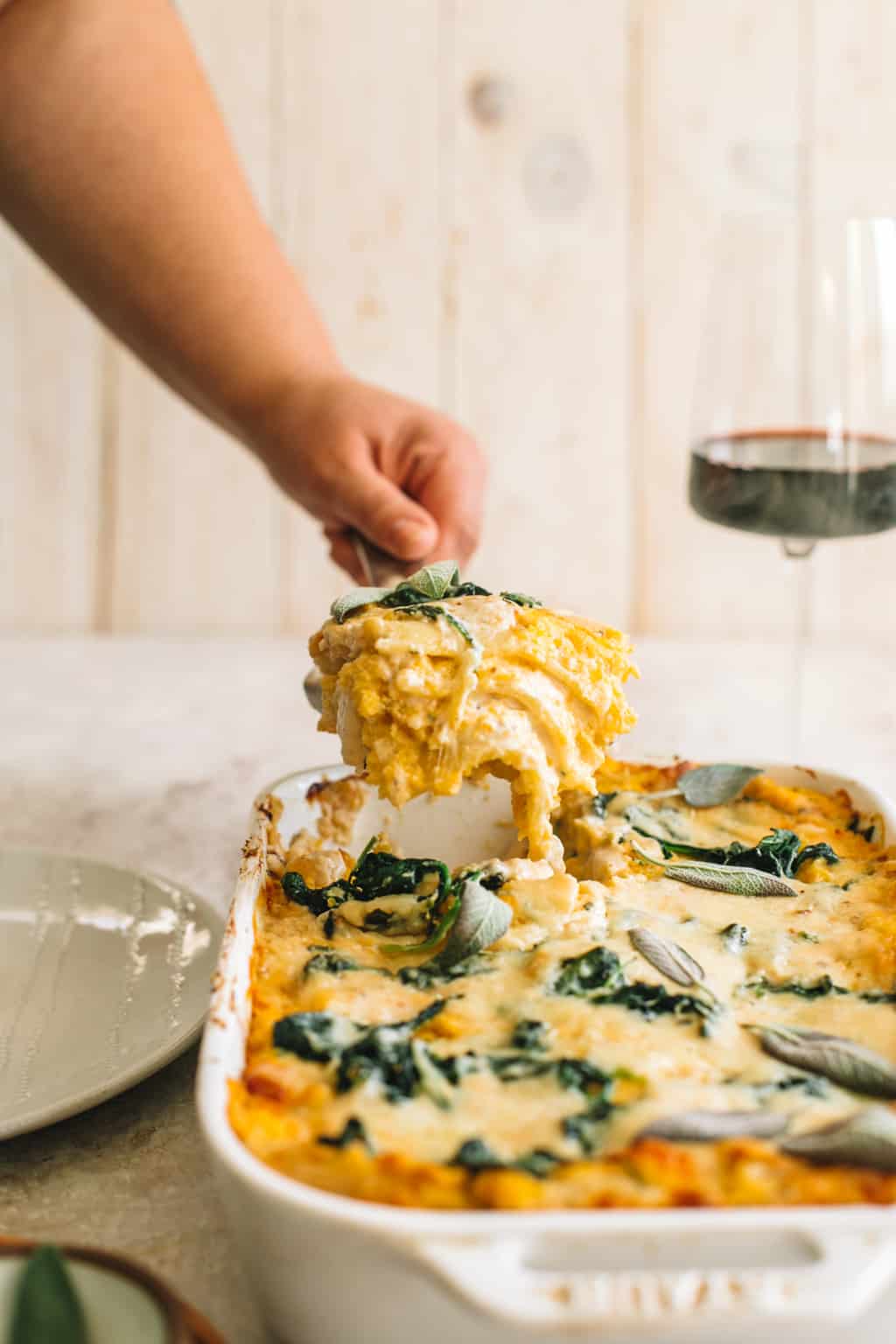 A slice of lasagna being pulled out of casserole dish. 