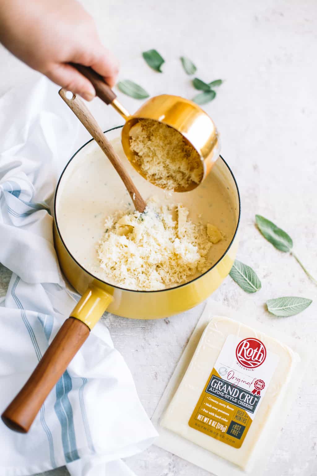 Grand cru cheese being poured into a yellow sauce pot of white sauce. 