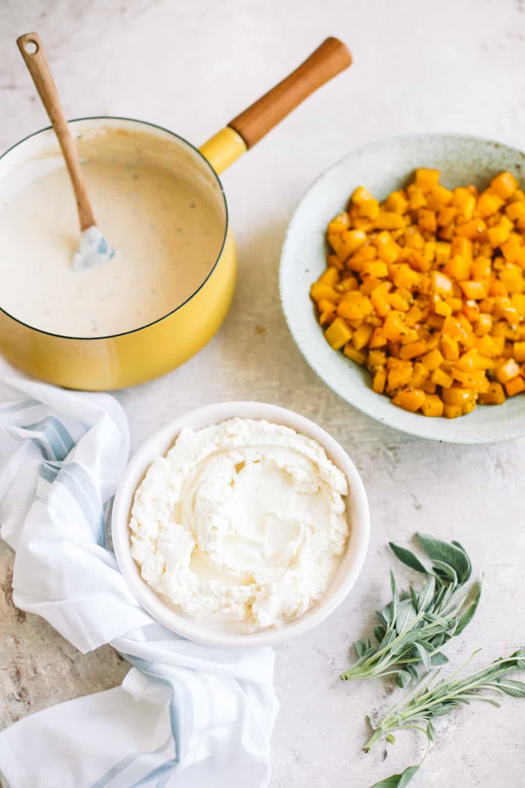 Bowls of white béchamel sauce, ricotta cheese and roasted butternut squash. 